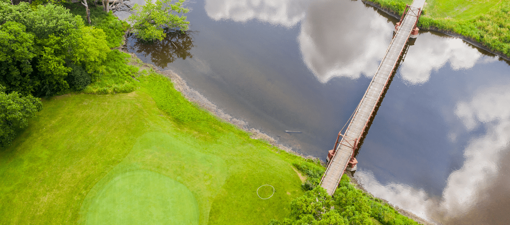 Aerial view of golf course with bridge over pond